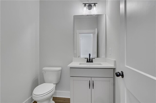 bathroom with hardwood / wood-style flooring, vanity, and toilet