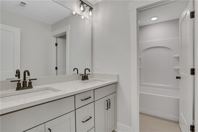 bathroom featuring vanity, a washtub, and tile patterned floors