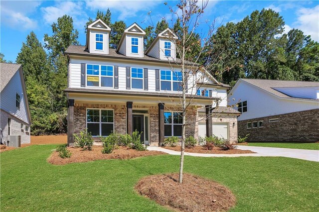 view of front of home featuring cooling unit, a garage, a porch, and a front lawn