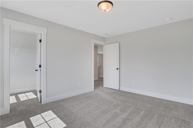 unfurnished bedroom with carpet flooring, a spacious closet, and a closet