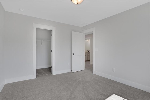 unfurnished bedroom with a spacious closet, light colored carpet, and a closet