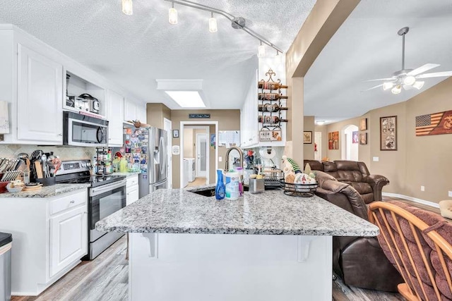 835 Custom Ln, Winder, GA 30680 - kitchen with stainless steel appliances, a sink, open floor plan, white cabinetry, and a breakfast bar
