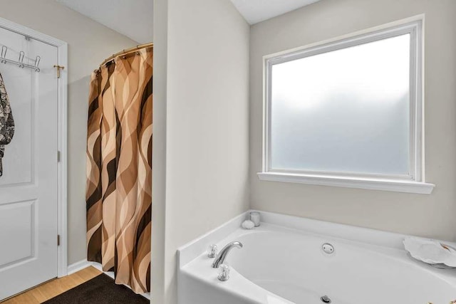 835 Custom Ln, Winder, GA 30680 - bathroom with healthy amount of natural light, a garden tub, and wood finished floors
