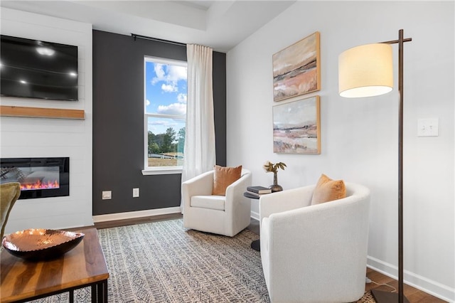 living area featuring hardwood / wood-style flooring and a large fireplace