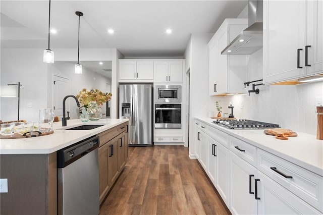 kitchen with wall chimney exhaust hood, sink, white cabinetry, an island with sink, and stainless steel appliances