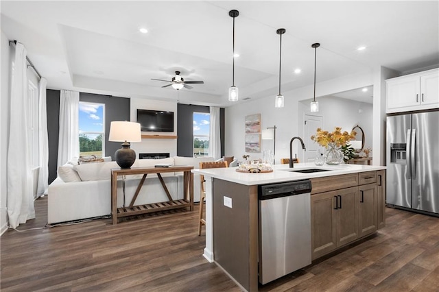 kitchen featuring a raised ceiling, sink, white cabinets, an island with sink, and stainless steel appliances