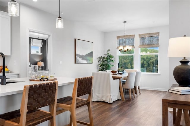 dining space with dark wood-type flooring, sink, and an inviting chandelier