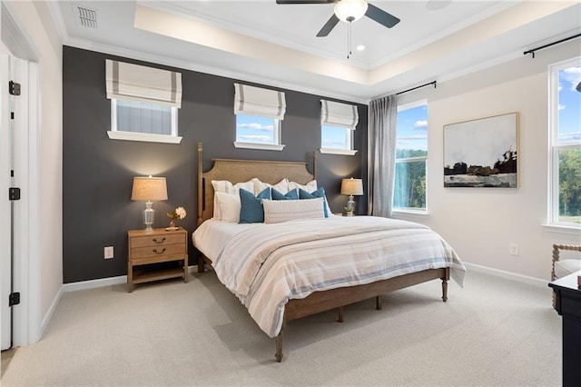 bedroom with ceiling fan, a tray ceiling, ornamental molding, and light carpet