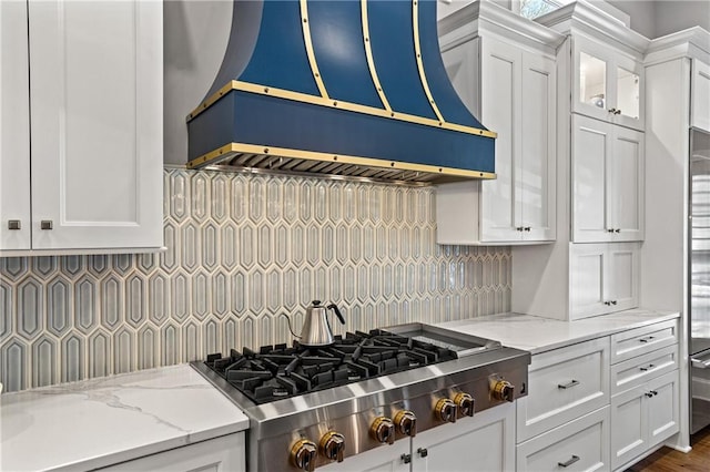 kitchen with premium range hood, white cabinetry, stainless steel gas stovetop, and light stone counters