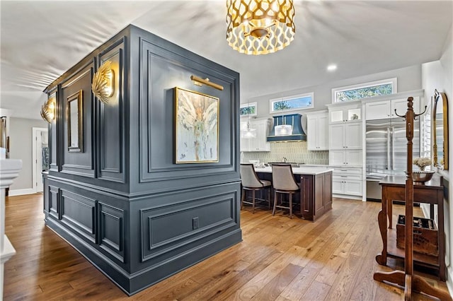 interior space featuring premium range hood, a kitchen island, decorative light fixtures, a breakfast bar area, and white cabinets