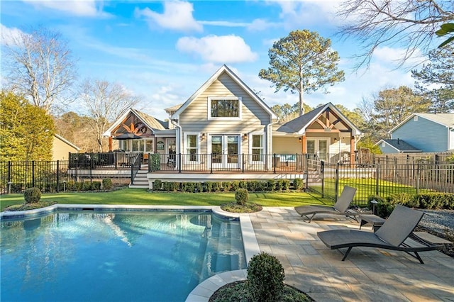 back of house featuring french doors, a swimming pool side deck, a patio area, and a lawn