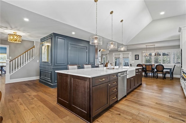 kitchen featuring vaulted ceiling, decorative light fixtures, an island with sink, dishwasher, and sink