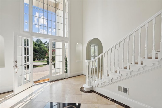 entrance foyer featuring a high ceiling, french doors, and light tile flooring