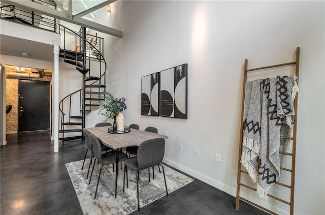 dining space featuring stairs, a high ceiling, concrete flooring, and baseboards