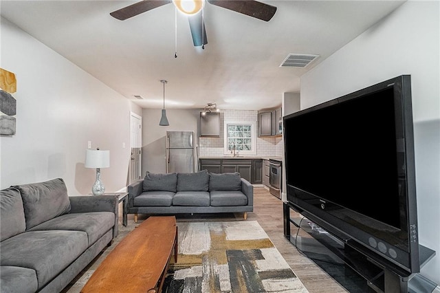 living room with ceiling fan, sink, and light hardwood / wood-style flooring