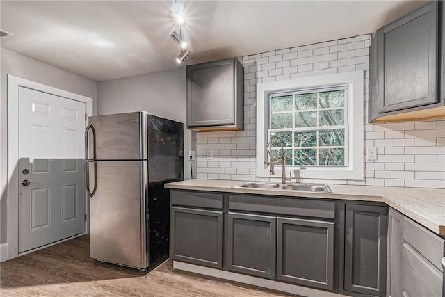 kitchen with gray cabinets, sink, stainless steel refrigerator, and track lighting