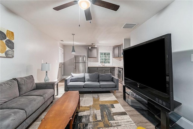 living room with ceiling fan, sink, and light hardwood / wood-style flooring