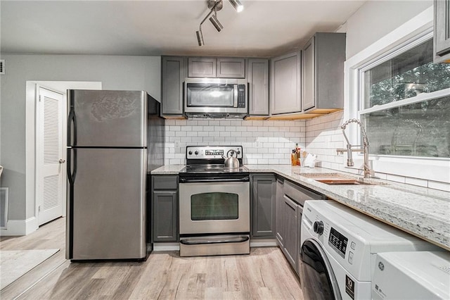 kitchen with decorative backsplash, stainless steel appliances, sink, washer / dryer, and gray cabinets