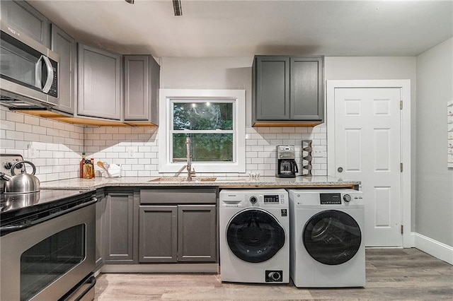 laundry room featuring light hardwood / wood-style floors, washing machine and dryer, and sink