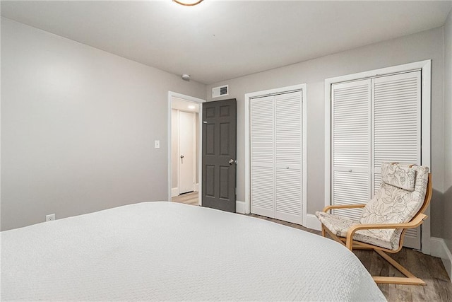 bedroom with light hardwood / wood-style floors and multiple closets