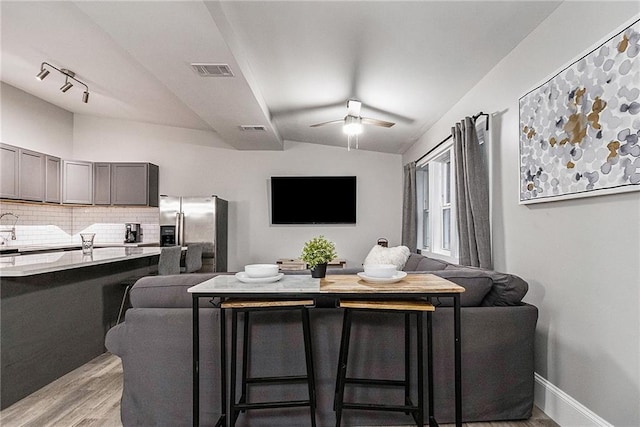 living room with light hardwood / wood-style floors, ceiling fan, and lofted ceiling