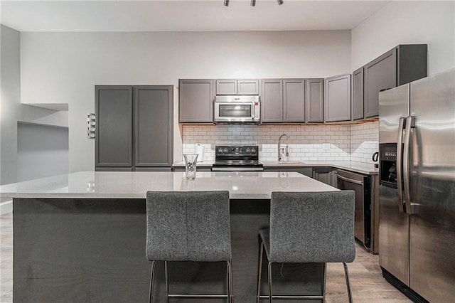 kitchen featuring decorative backsplash, light stone counters, stainless steel appliances, and a kitchen island with sink