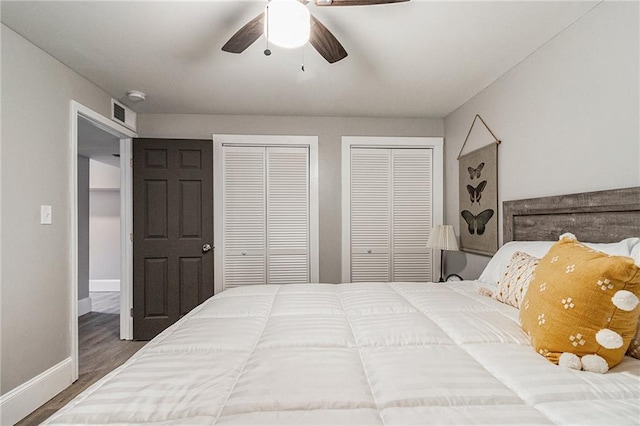 bedroom with multiple closets, ceiling fan, and wood-type flooring