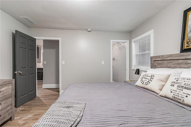 bedroom with hardwood / wood-style flooring, a walk in closet, and a closet