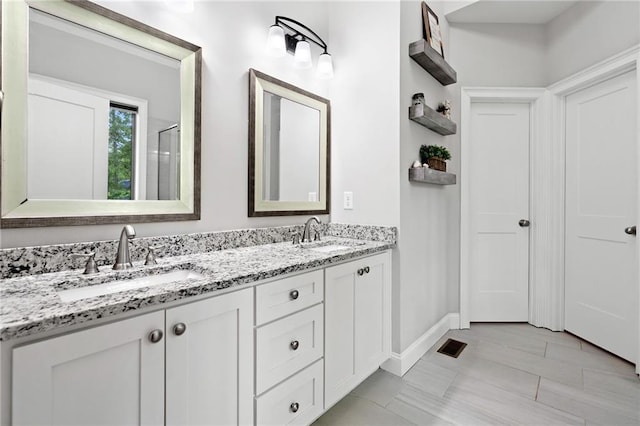 full bath with a sink, baseboards, double vanity, and visible vents