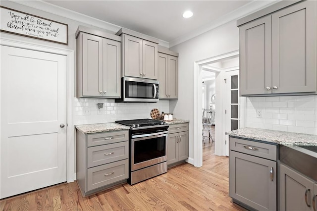 kitchen featuring ornamental molding, gray cabinets, and appliances with stainless steel finishes