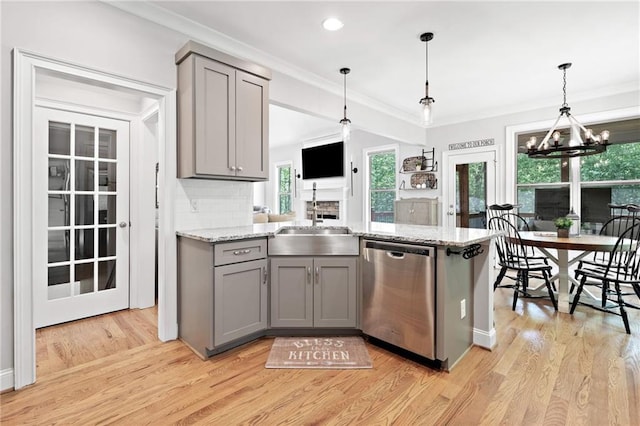 kitchen with stainless steel dishwasher, a sink, light wood finished floors, and gray cabinetry
