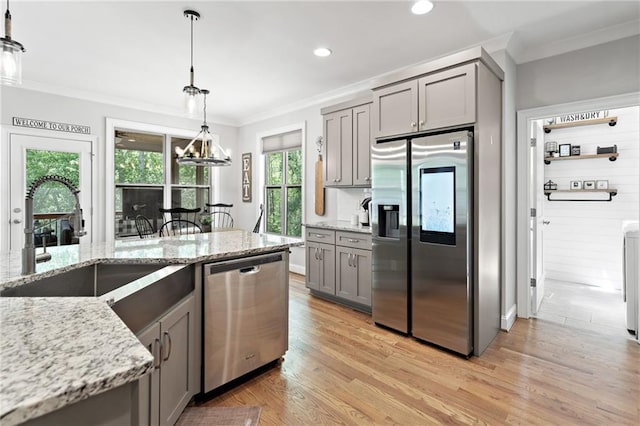 kitchen with gray cabinets, crown molding, appliances with stainless steel finishes, a sink, and light wood-style floors