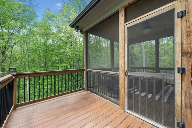 wooden terrace featuring a sunroom and a view of trees