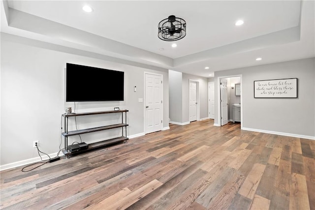 unfurnished living room with recessed lighting, baseboards, wood finished floors, and a raised ceiling
