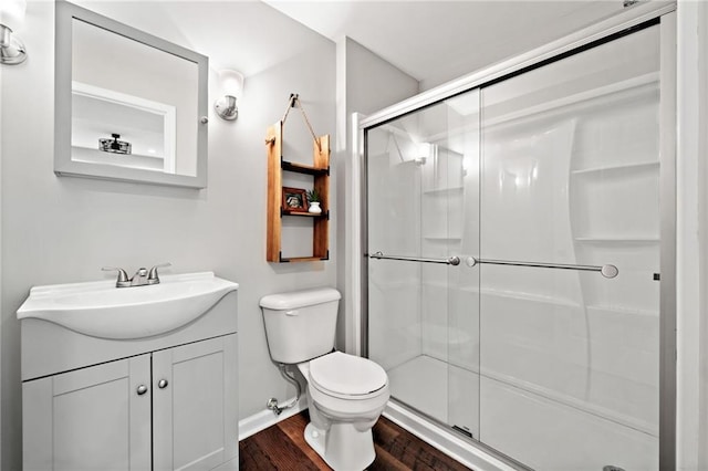 bathroom featuring a stall shower, wood finished floors, vanity, baseboards, and toilet