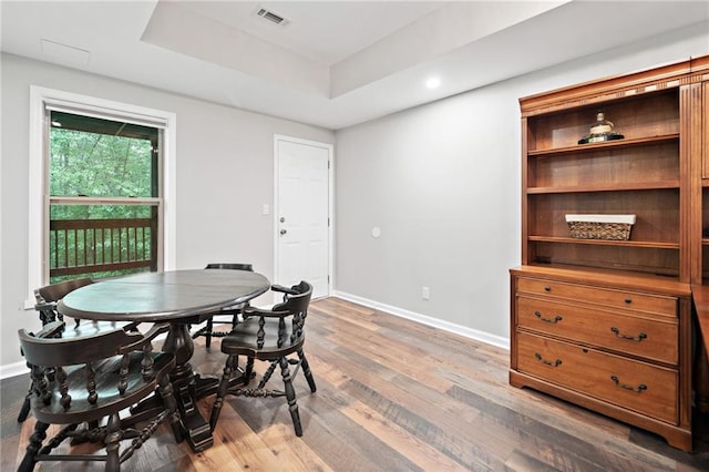 dining room featuring visible vents, wood finished floors, baseboards, a tray ceiling, and recessed lighting
