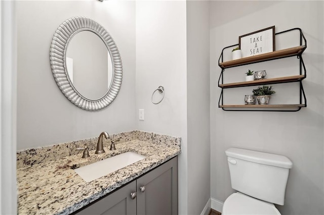 bathroom featuring toilet, baseboards, and vanity