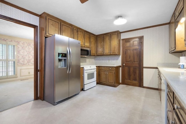 kitchen with wallpapered walls, appliances with stainless steel finishes, ornamental molding, a wainscoted wall, and light countertops