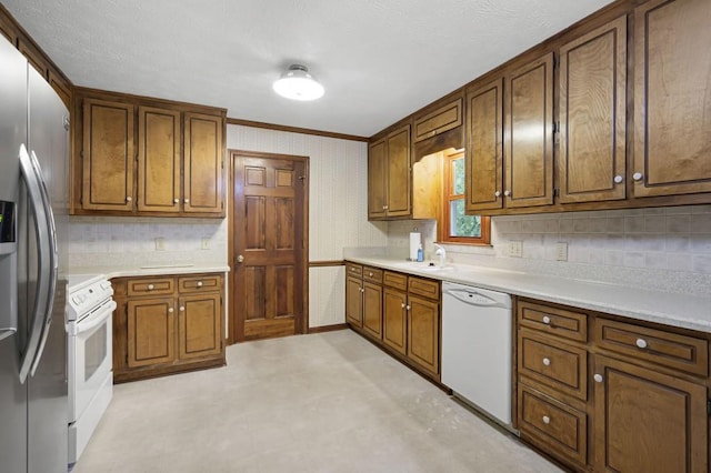 kitchen with white appliances, backsplash, light countertops, brown cabinets, and a sink