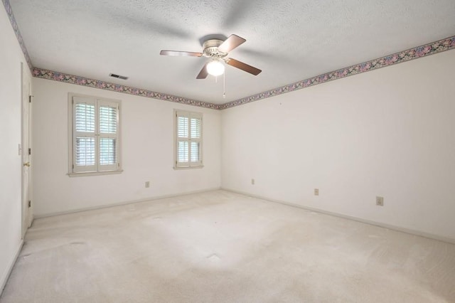 spare room with a ceiling fan, carpet flooring, baseboards, and a textured ceiling