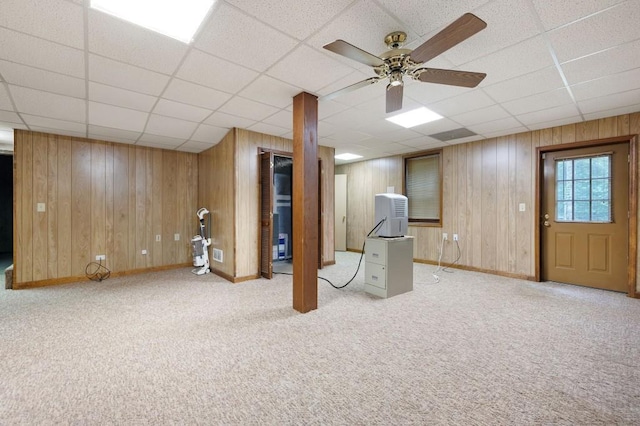 below grade area with wood walls, a paneled ceiling, carpet, and baseboards