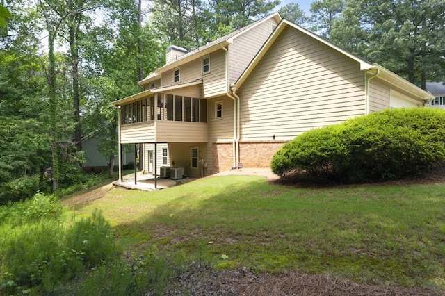 back of house featuring a sunroom, a patio area, a lawn, and a chimney