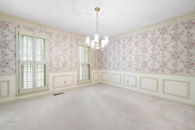 carpeted spare room with a chandelier, wainscoting, wallpapered walls, and crown molding