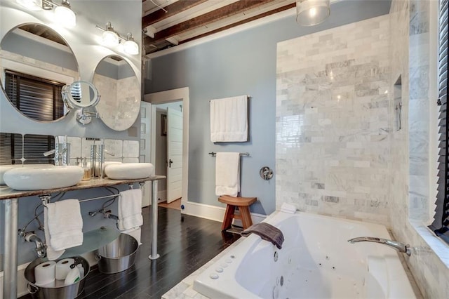 bathroom featuring hardwood / wood-style flooring, a relaxing tiled tub, beam ceiling, and sink