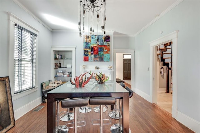 dining room featuring crown molding, plenty of natural light, and wood-type flooring