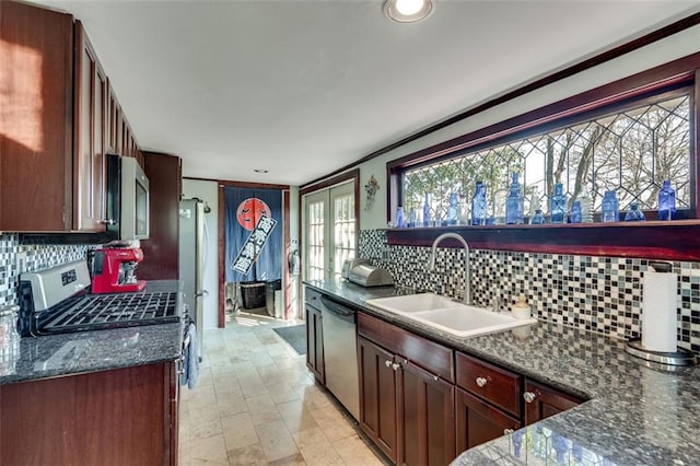 kitchen with sink, french doors, tasteful backsplash, dark stone counters, and appliances with stainless steel finishes