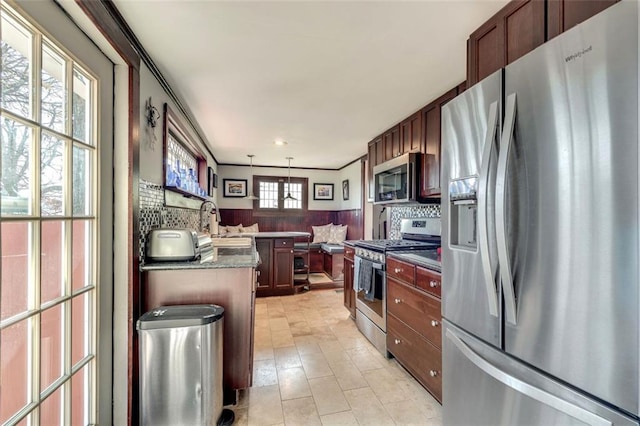 kitchen featuring pendant lighting, backsplash, sink, kitchen peninsula, and stainless steel appliances