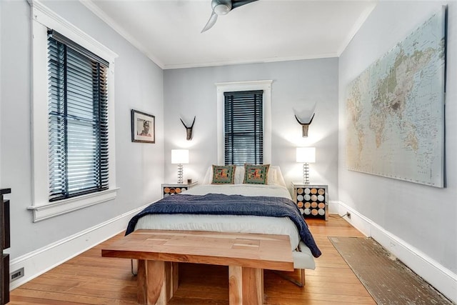 bedroom with light wood-type flooring, ceiling fan, and crown molding