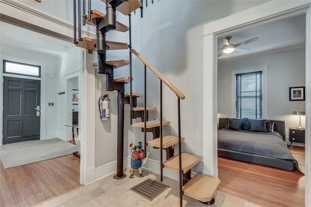 stairway featuring ceiling fan, hardwood / wood-style flooring, and ornamental molding