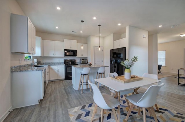 kitchen featuring white cabinetry, a center island, and black appliances